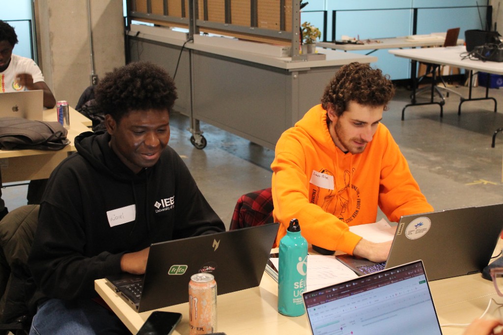 Two students working on laptops at a workshop bench