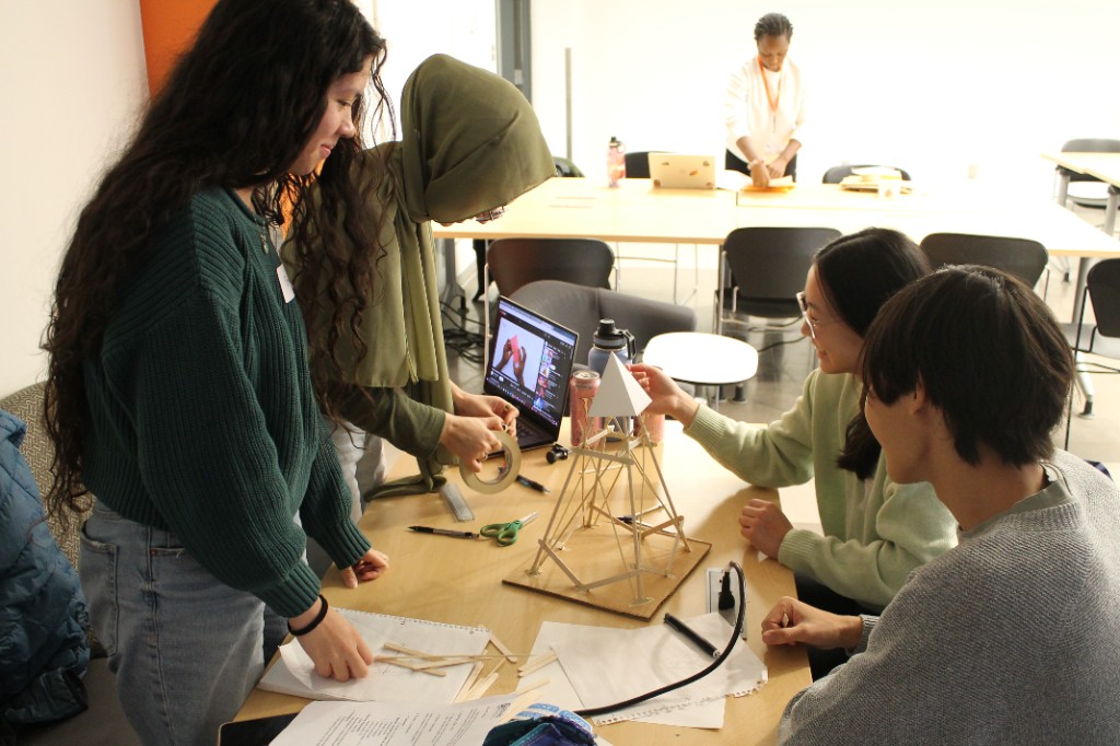 A team building a popsicle-stick structure at a table