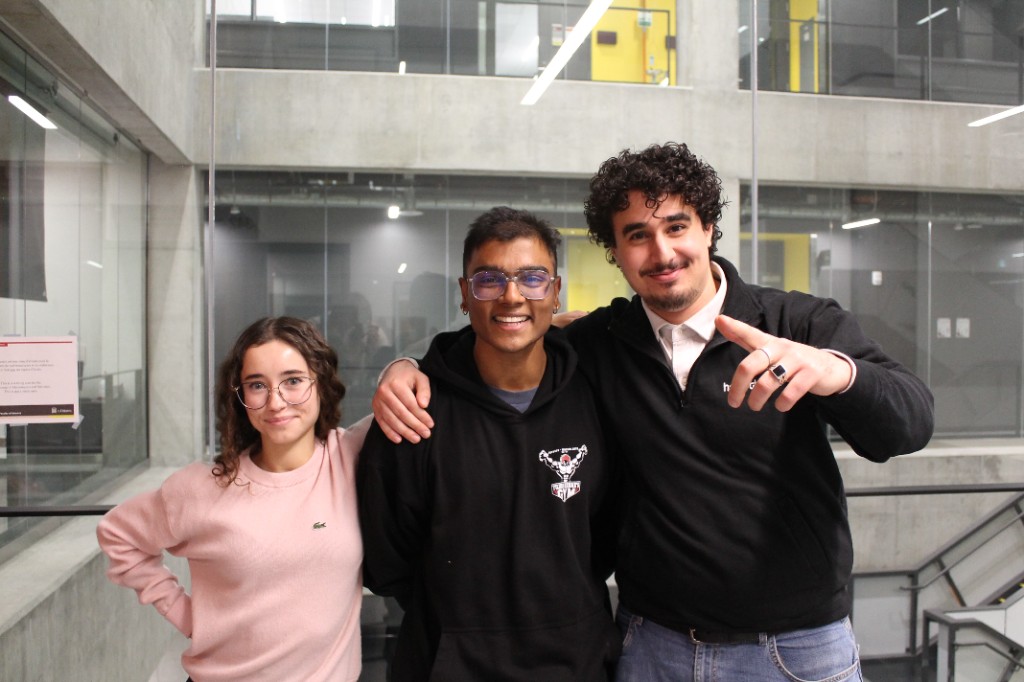 Three students posing together in a campus atrium