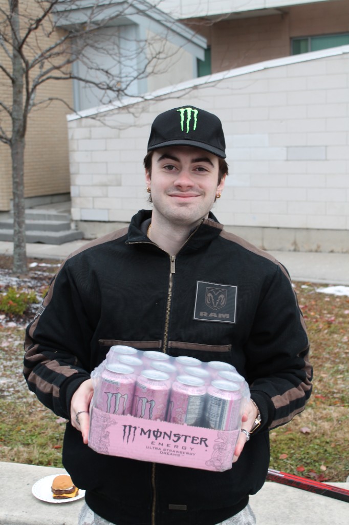 A student holding a case of energy drinks on campus